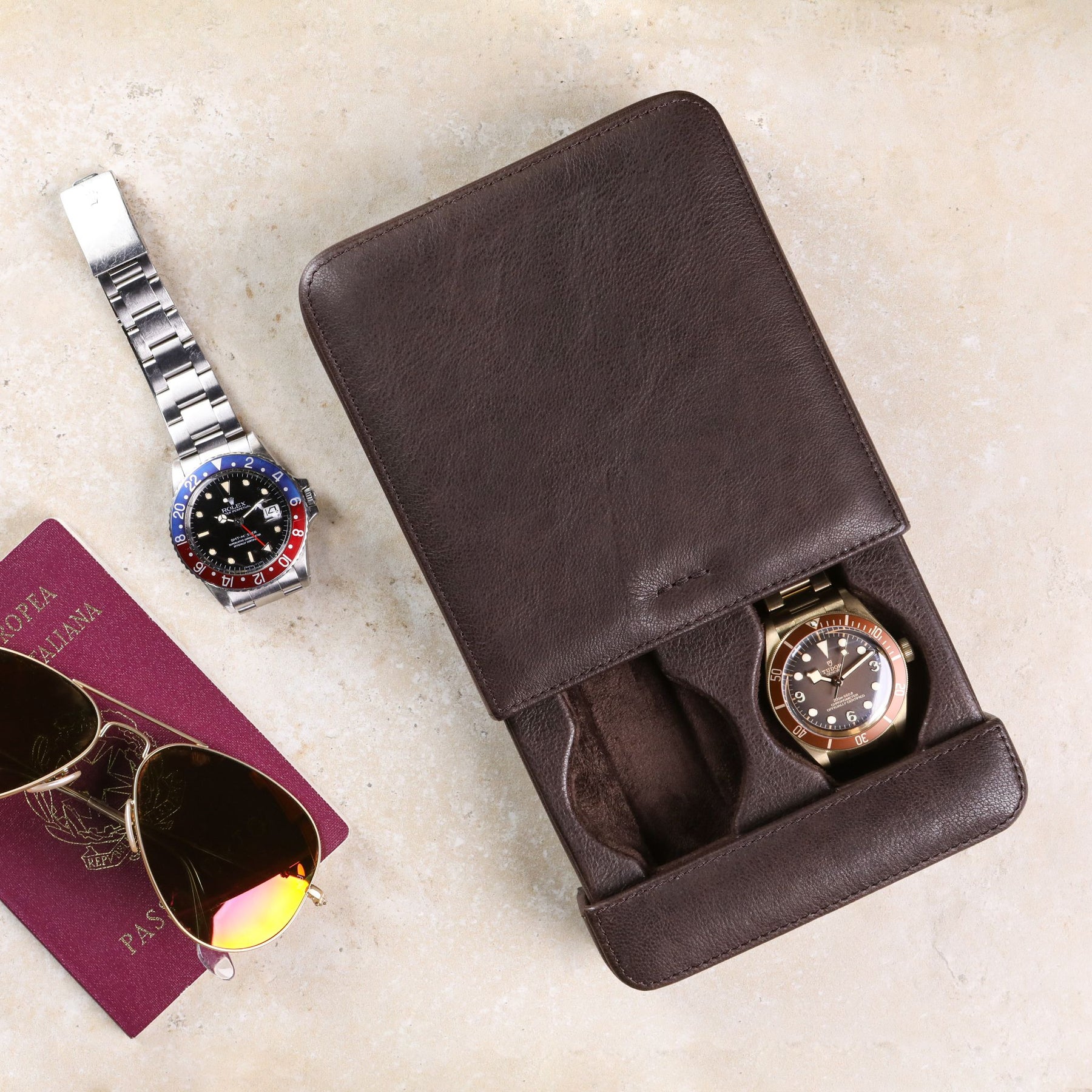 Porta orologi a scorrimento in pelle lavata color testa di moro con passaporto, occhiali da aviatore, Tudor Bronze e Rolex GMT Master II